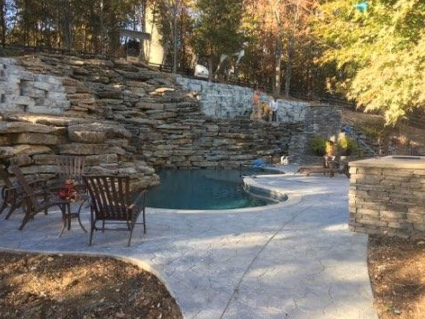 A pool with chairs and rocks around it